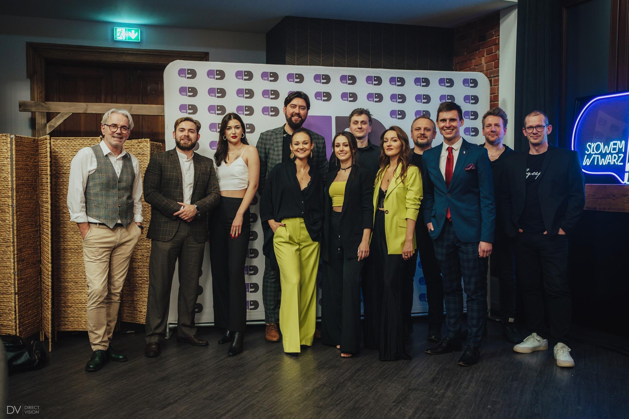 Group photo of artists and organizers in front of the backdrop after the concert.