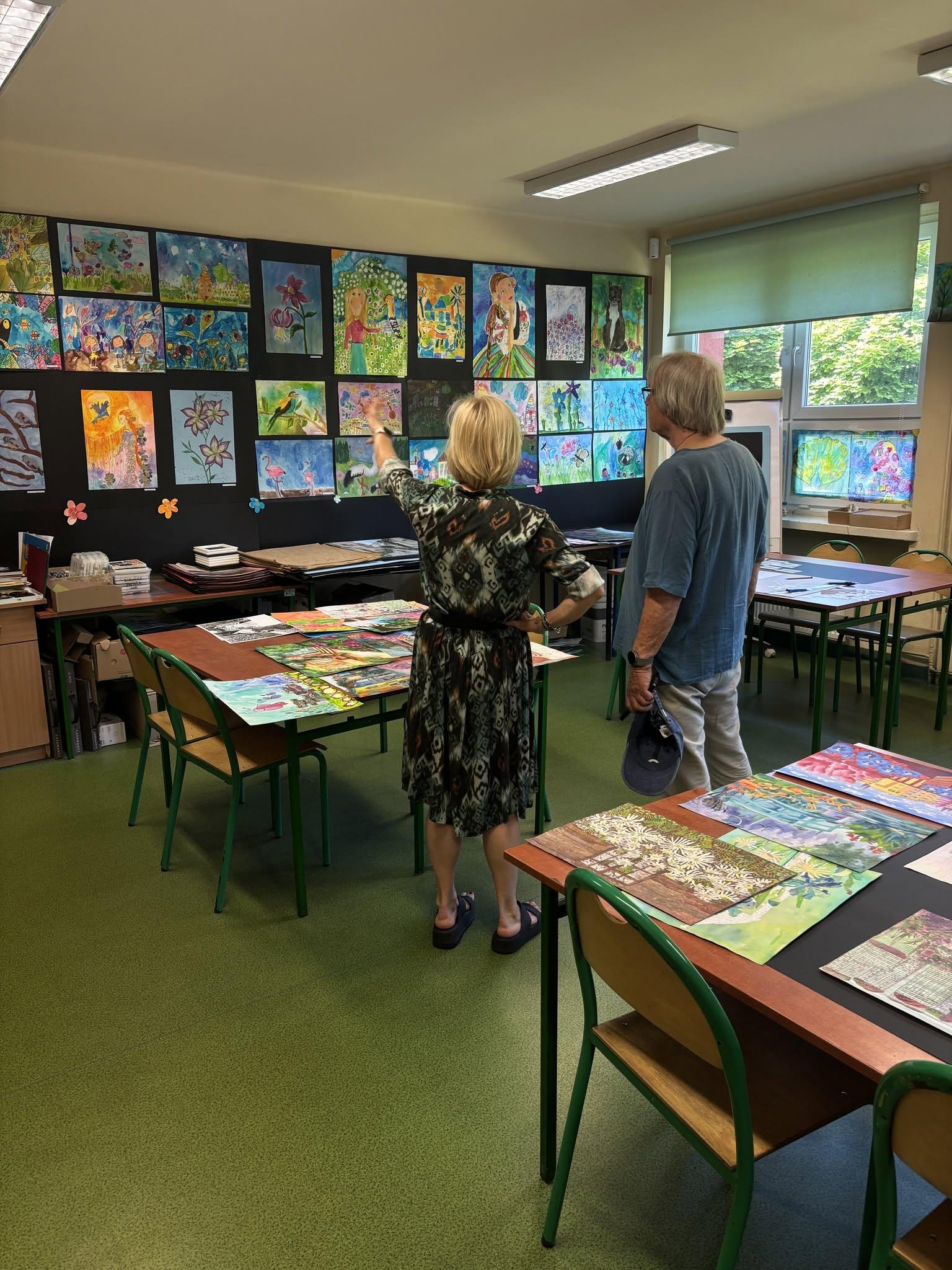 Study-visit participants viewing colourful artworks in a school art room