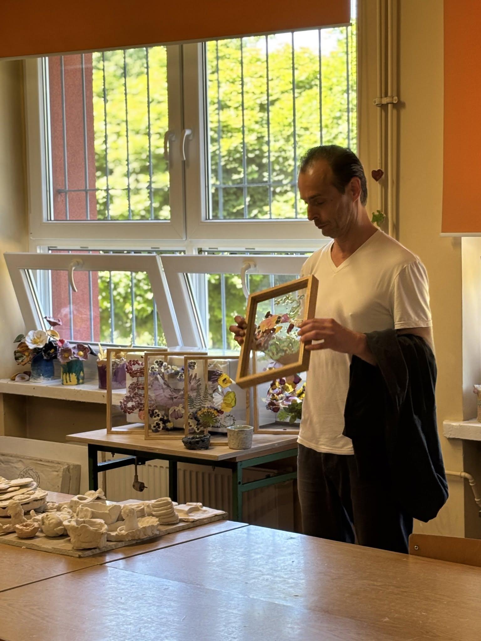 A participant presenting a framed glass composition in an art studio