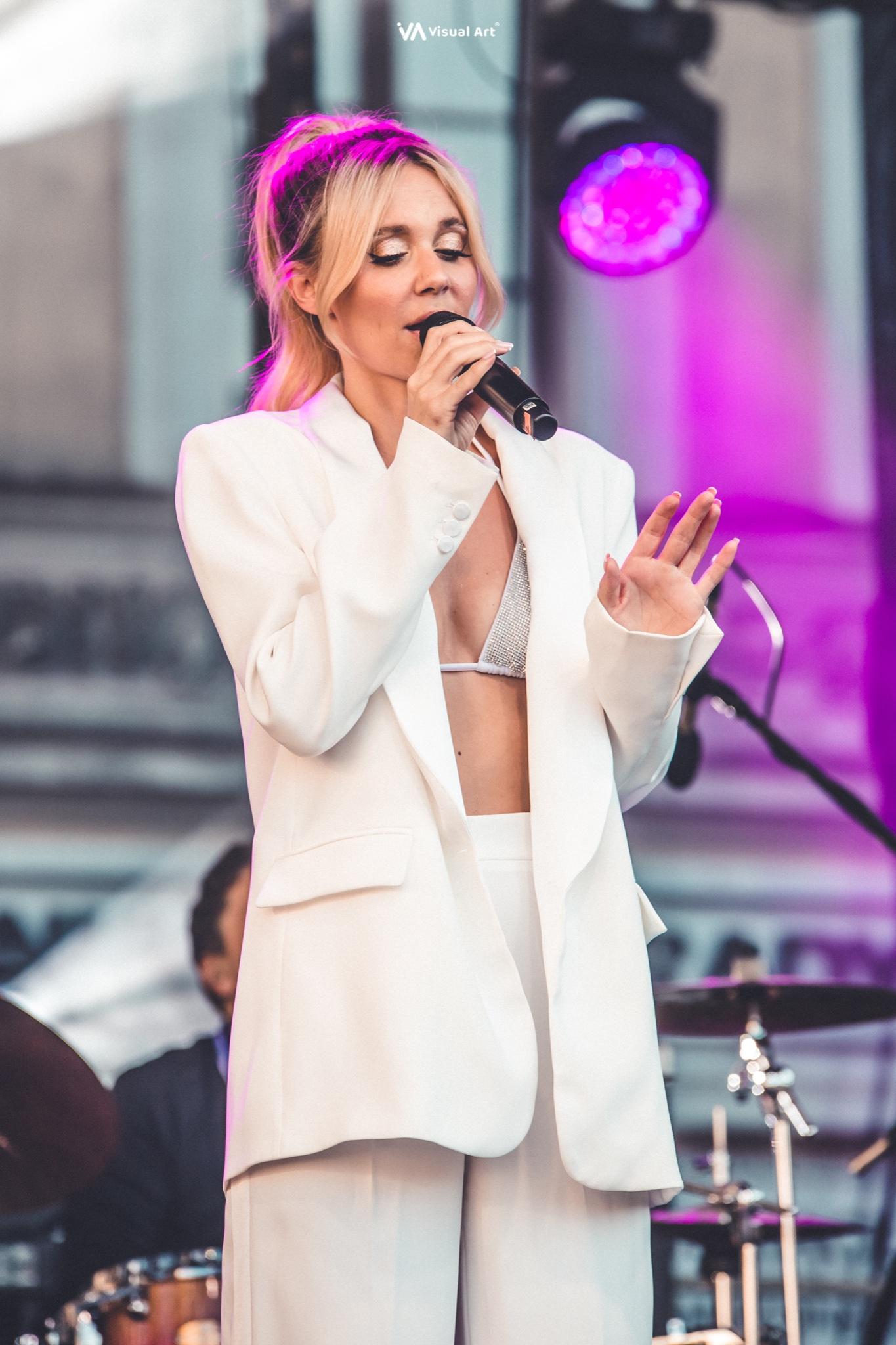 A musician plays bass guitar on stage during an outdoor concert.